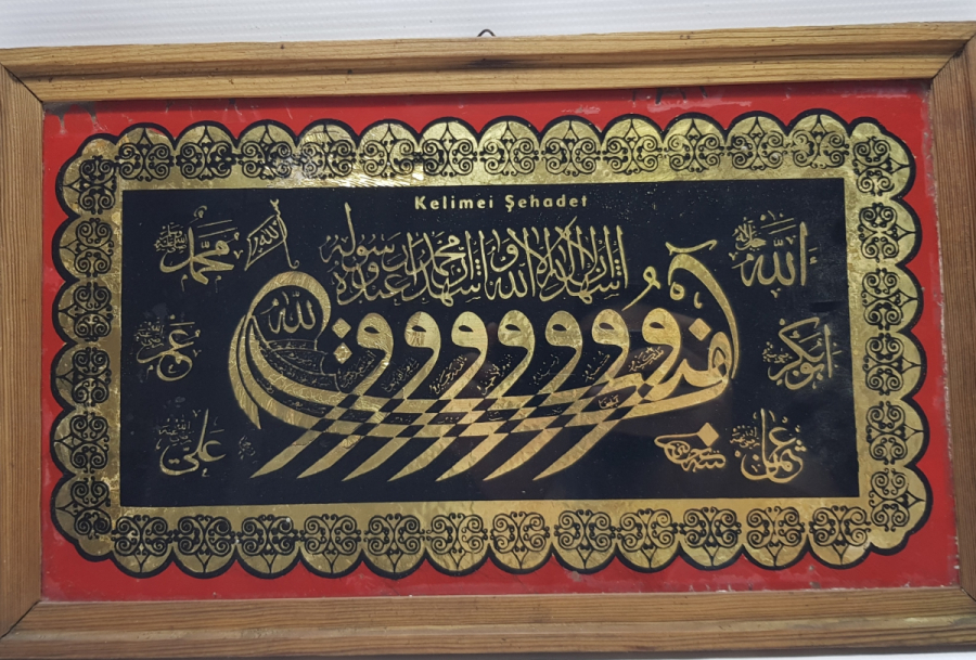 HÜSEYİN KETEBELİ VAV KAYIĞI FORMUNDA KELİME-İ ŞEHADET YAZILI CAM ALTI HAT LEVHA